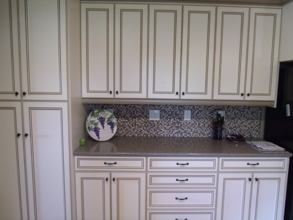 Inredning av ett klassiskt mellanstort kök, med en dubbel diskho, luckor med infälld panel, vita skåp, laminatbänkskiva, flerfärgad stänkskydd, stänkskydd i mosaik, ljust trägolv och en halv köksö