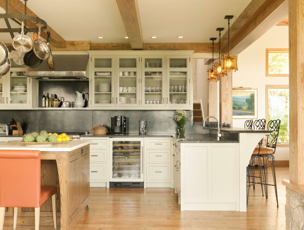 Foto di un cucina con isola centrale country con ante di vetro, paraspruzzi grigio, pavimento in legno massello medio e ante beige