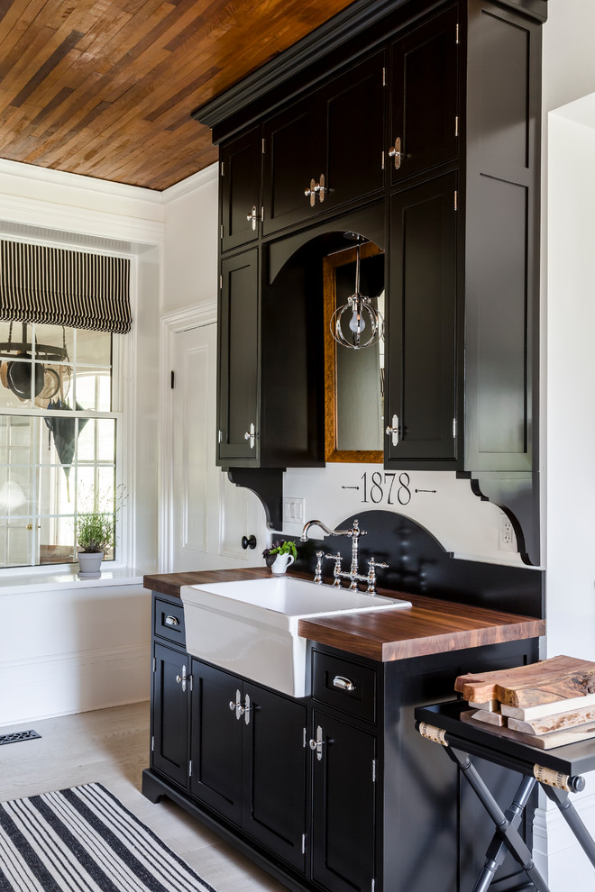 Photo of a farmhouse kitchen in Other with a belfast sink, shaker cabinets, wood worktops, light hardwood flooring, brown worktops and beige floors.