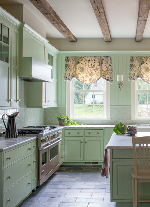 Farmhouse kitchen with soft green cabinets, rustic wood beams, and cozy natural light