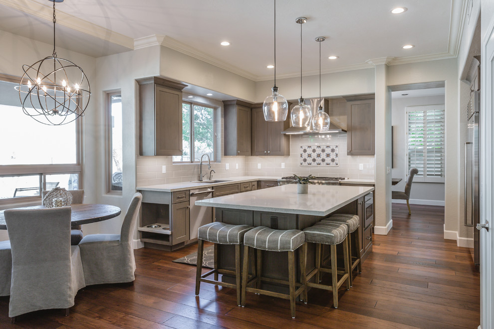Mid-sized country l-shaped dark wood floor and brown floor eat-in kitchen photo in Phoenix with an undermount sink, shaker cabinets, dark wood cabinets, solid surface countertops, white backsplash, subway tile backsplash, stainless steel appliances, an island and white countertops