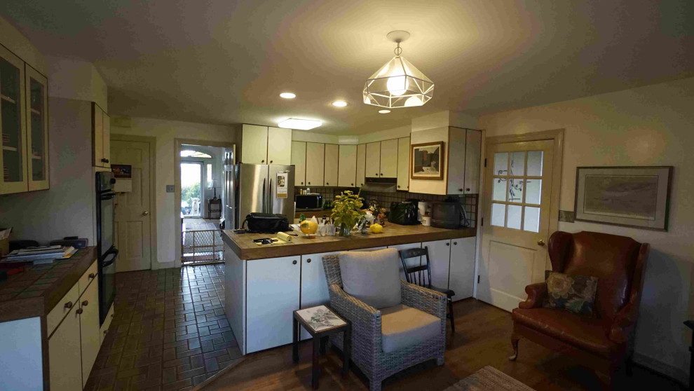 Foto på ett mellanstort lantligt beige kök, med en undermonterad diskho, släta luckor, vita skåp, granitbänkskiva, rostfria vitvaror, mellanmörkt trägolv, en köksö och brunt golv