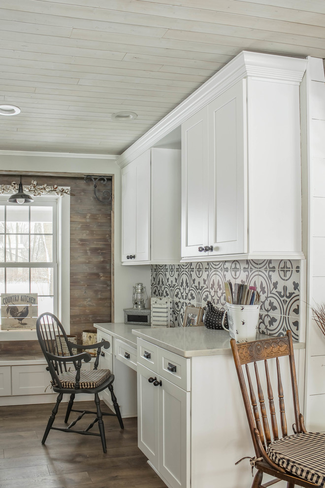 Inspiration for a large country u-shaped kitchen/diner in Detroit with a belfast sink, shaker cabinets, white cabinets, engineered stone countertops, white splashback, metro tiled splashback, stainless steel appliances, medium hardwood flooring, an island, brown floors and white worktops.