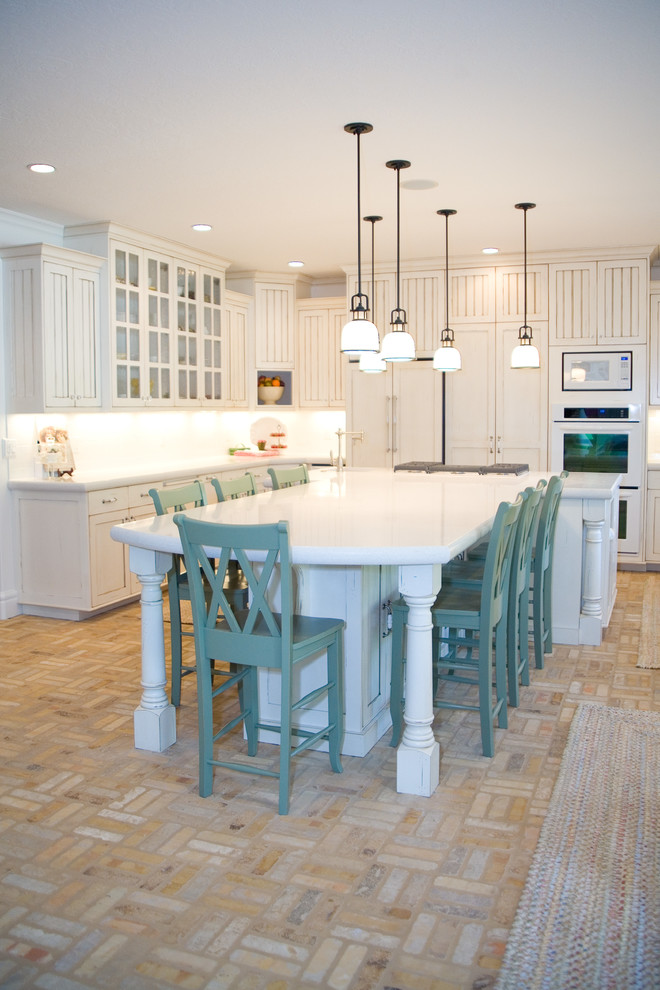 Photo of a large country u-shaped kitchen/diner in Salt Lake City with a submerged sink, beaded cabinets, white cabinets, marble worktops, white splashback, metro tiled splashback, white appliances, brick flooring and an island.