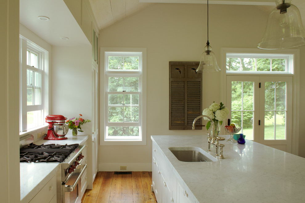 Mid-sized farmhouse light wood floor eat-in kitchen photo in Boston with an undermount sink, shaker cabinets, white cabinets, marble countertops, white backsplash, stone slab backsplash and an island