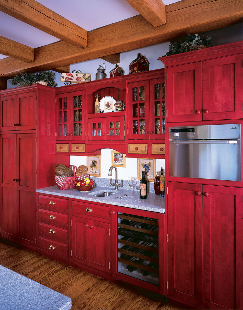 Modelo de cocina de estilo de casa de campo de obra con armarios estilo shaker, fregadero bajoencimera, puertas de armario rojas y electrodomésticos de acero inoxidable