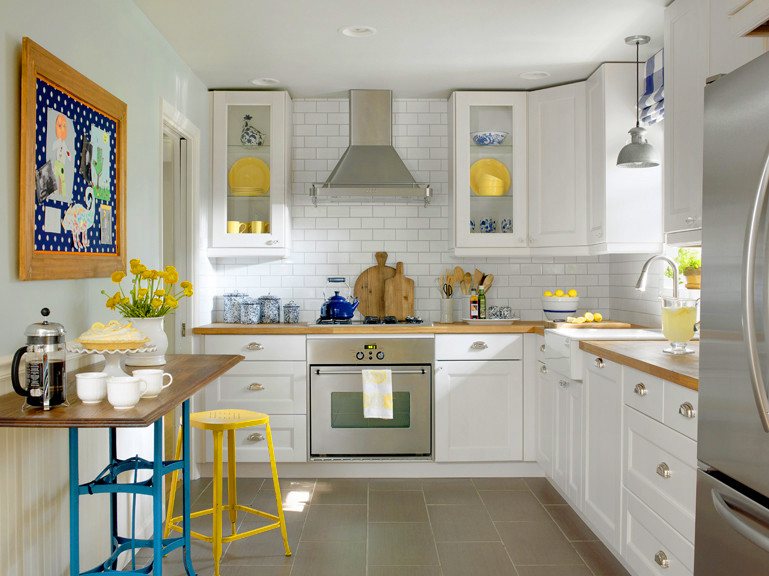 Design ideas for a small farmhouse galley kitchen/diner in St Louis with a belfast sink, shaker cabinets, white cabinets, wood worktops, white splashback, metro tiled splashback, stainless steel appliances, porcelain flooring and no island.