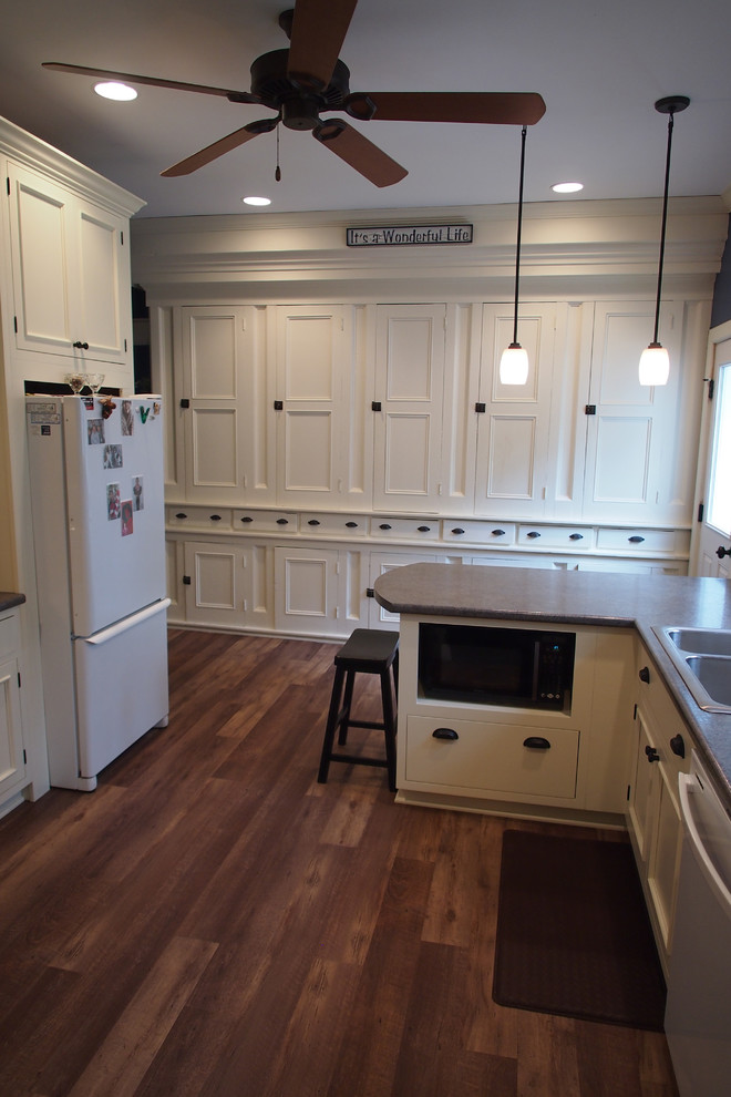 Example of a farmhouse l-shaped eat-in kitchen design in Grand Rapids with raised-panel cabinets, white cabinets and white appliances