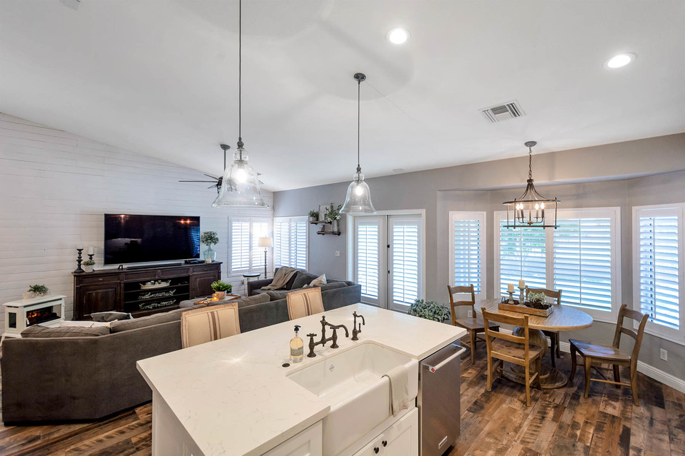 Large farmhouse l-shaped open plan kitchen in Phoenix with a belfast sink, shaker cabinets, white cabinets, engineered stone countertops, white splashback, metro tiled splashback, stainless steel appliances, an island and white worktops.