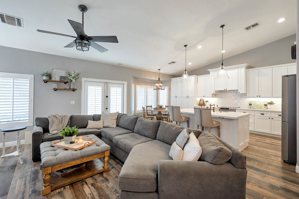 Example of a large cottage l-shaped open concept kitchen design in Phoenix with a farmhouse sink, shaker cabinets, white cabinets, quartz countertops, white backsplash, subway tile backsplash, stainless steel appliances, an island and white countertops