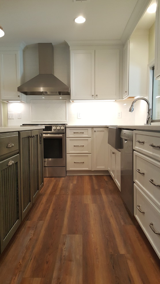Eat-in kitchen - country u-shaped vinyl floor and multicolored floor eat-in kitchen idea in Other with a farmhouse sink, shaker cabinets, white cabinets, quartz countertops, white backsplash, subway tile backsplash, stainless steel appliances, an island and white countertops
