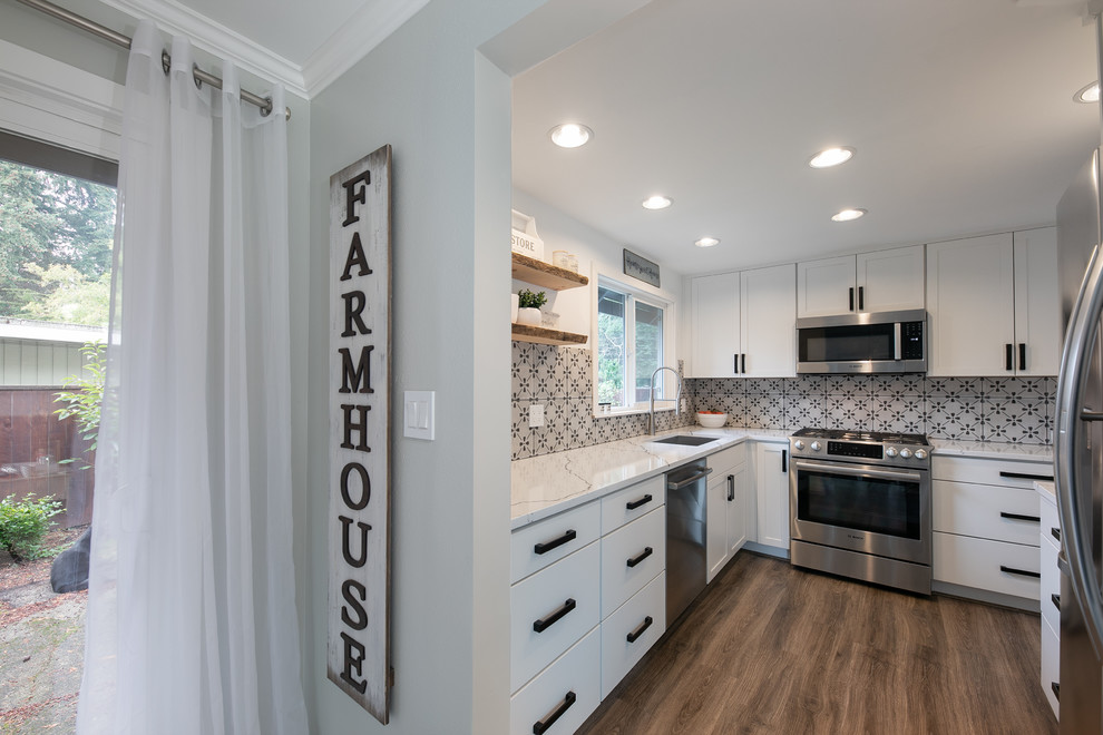 Example of a mid-sized farmhouse u-shaped light wood floor and gray floor enclosed kitchen design in Seattle with an undermount sink, shaker cabinets, white cabinets, quartz countertops, gray backsplash, ceramic backsplash, stainless steel appliances, no island and white countertops