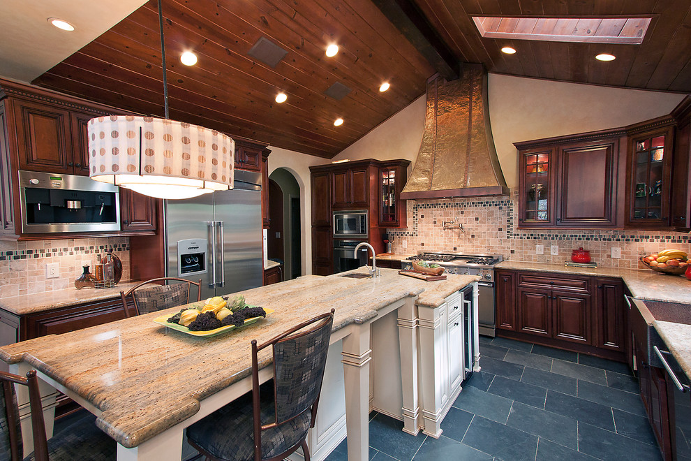 Bild på ett stort vintage kök, med en rustik diskho, luckor med upphöjd panel, skåp i mörkt trä, granitbänkskiva, flerfärgad stänkskydd, stänkskydd i stenkakel, rostfria vitvaror, travertin golv, en köksö och svart golv