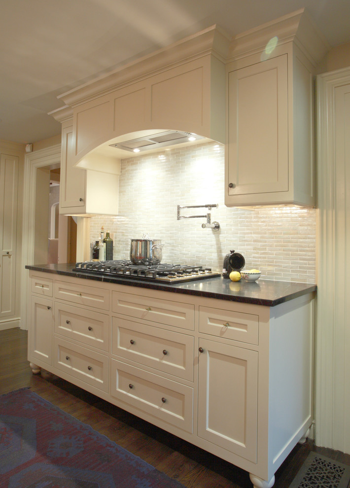 Exempel på ett stort lantligt kök, med släta luckor, vita skåp, bänkskiva i täljsten, flerfärgad stänkskydd, stänkskydd i glaskakel, svarta vitvaror och en köksö