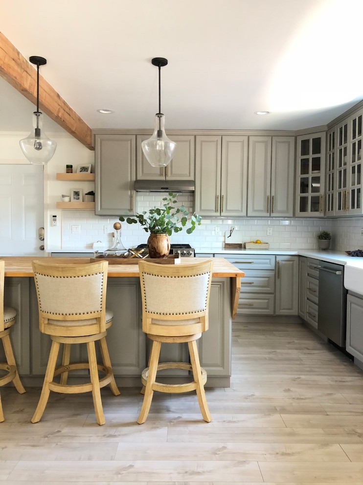 Small farmhouse l-shaped light wood floor and beige floor open concept kitchen photo in Orange County with raised-panel cabinets, gray cabinets, an island, a farmhouse sink, quartz countertops, white backsplash, subway tile backsplash, stainless steel appliances and white countertops