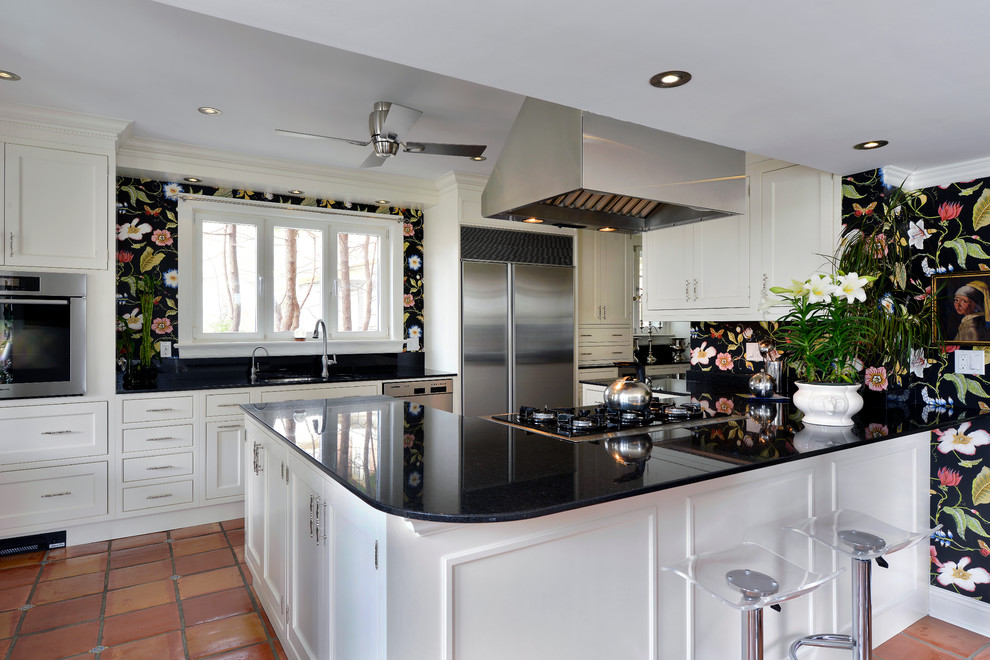 Inredning av ett lantligt kök och matrum, med en undermonterad diskho, skåp i shakerstil, vita skåp, rostfria vitvaror, en halv köksö och klinkergolv i terrakotta