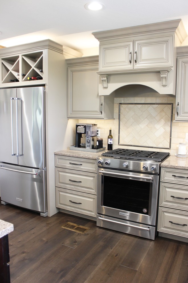 Example of a large country l-shaped medium tone wood floor and gray floor open concept kitchen design in Other with an undermount sink, raised-panel cabinets, beige cabinets, quartz countertops, beige backsplash, porcelain backsplash, stainless steel appliances, an island and beige countertops