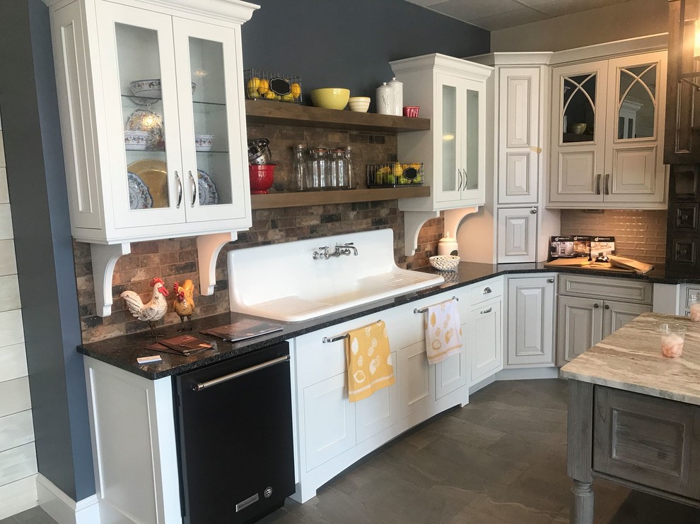 Example of a large country l-shaped porcelain tile and brown floor kitchen design in Other with a drop-in sink, raised-panel cabinets, white cabinets, marble countertops, brown backsplash, stone tile backsplash, stainless steel appliances and an island