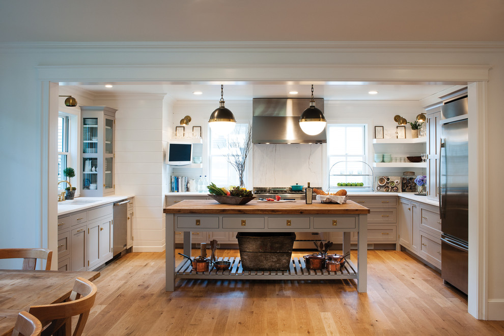 Inspiration for a country kitchen in Boston with flat-panel cabinets, grey cabinets, white splashback, stainless steel appliances, light hardwood flooring and an island.