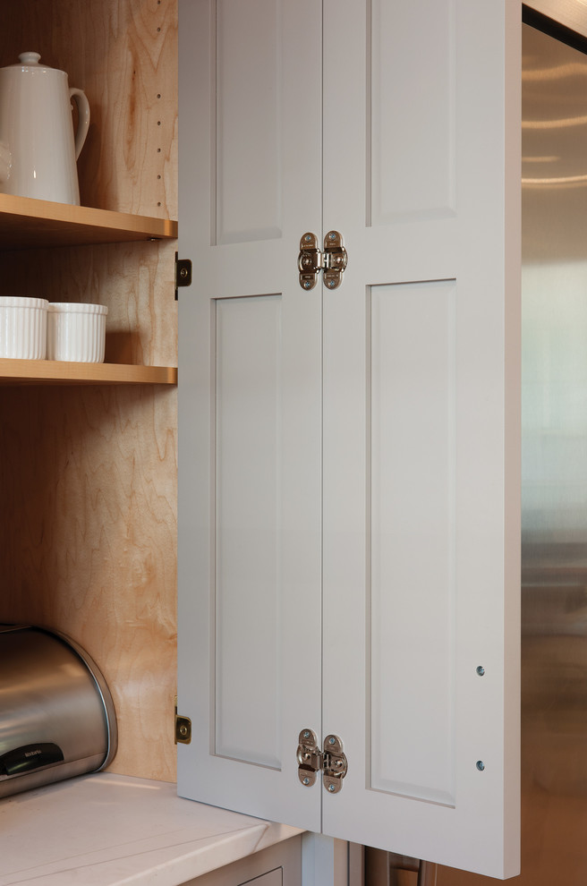 Exemple d'une cuisine nature en U avec un placard à porte plane, des portes de placard grises, une crédence blanche, un électroménager en acier inoxydable, parquet clair et îlot.