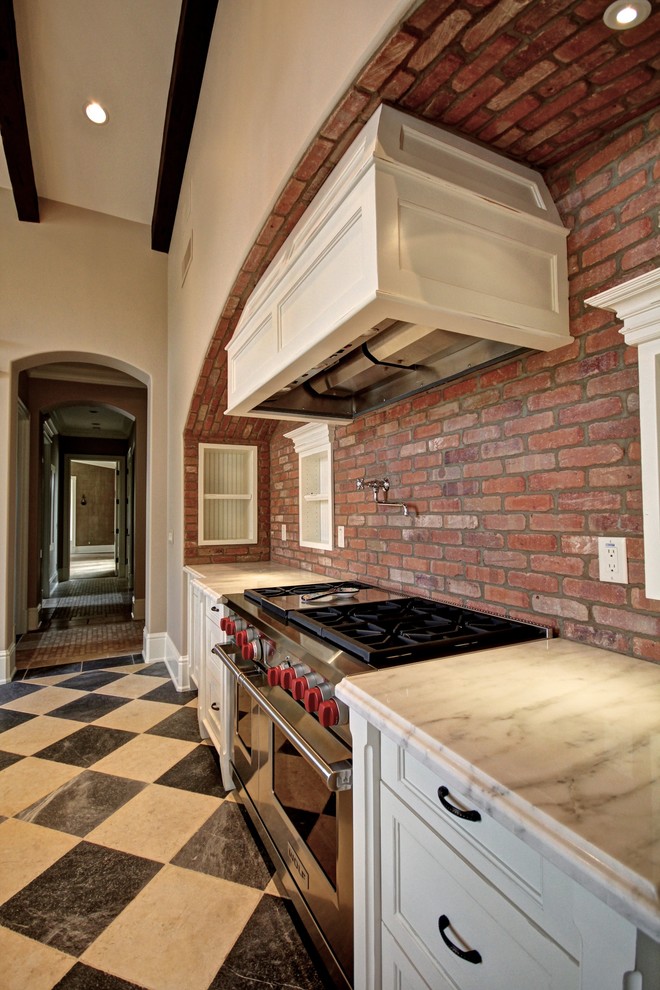 Exempel på ett avskilt, stort klassiskt u-kök, med luckor med infälld panel, vita skåp, marmorbänkskiva, rött stänkskydd, stänkskydd i tegel, rostfria vitvaror, klinkergolv i keramik, en rustik diskho och en köksö