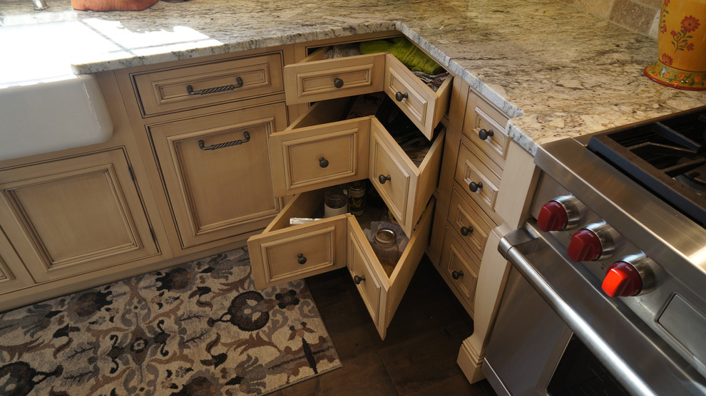 Lantlig inredning av ett mellanstort kök, med en rustik diskho, luckor med upphöjd panel, skåp i slitet trä, granitbänkskiva, beige stänkskydd, stänkskydd i stenkakel, integrerade vitvaror, mörkt trägolv och en köksö