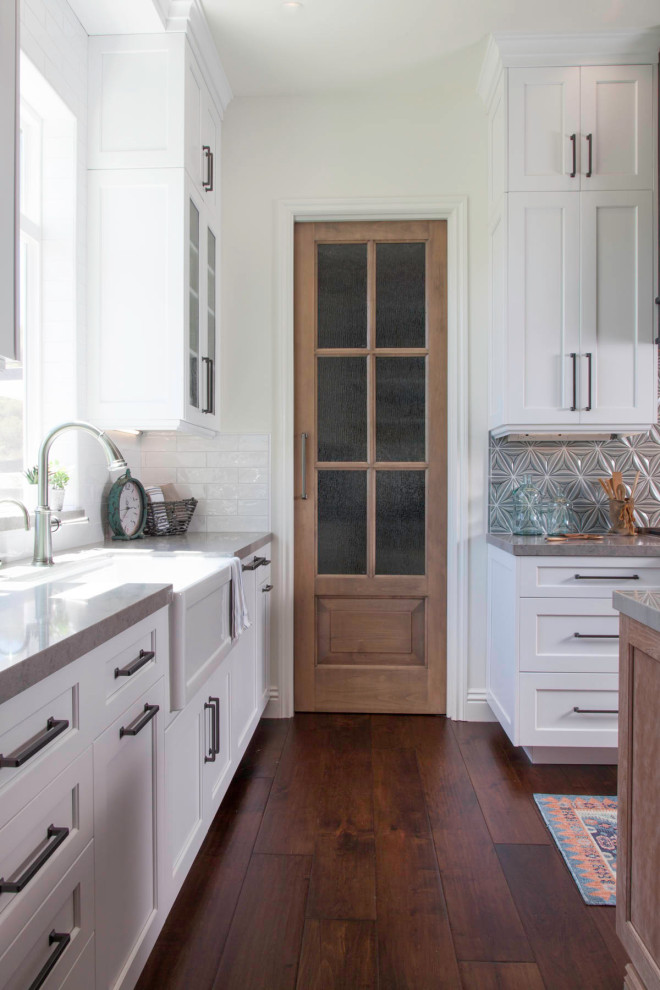 Foto på ett stort lantligt grå kök, med en rustik diskho, luckor med infälld panel, skåp i ljust trä, bänkskiva i kvartsit, blått stänkskydd, stänkskydd i keramik, rostfria vitvaror, mörkt trägolv, en köksö och brunt golv