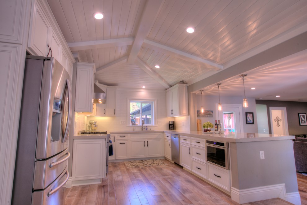Idéer för ett mellanstort lantligt grå kök, med en enkel diskho, släta luckor, vita skåp, bänkskiva i kvarts, vitt stänkskydd, stänkskydd i keramik, rostfria vitvaror, mellanmörkt trägolv, en halv köksö och grått golv