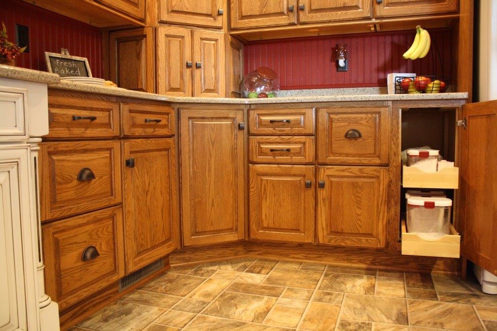 Cette image montre une petite cuisine américaine rustique en U et bois brun avec un évier encastré, un placard avec porte à panneau surélevé, un plan de travail en granite, une crédence rouge, une crédence en bois, un électroménager blanc, un sol en vinyl et îlot.