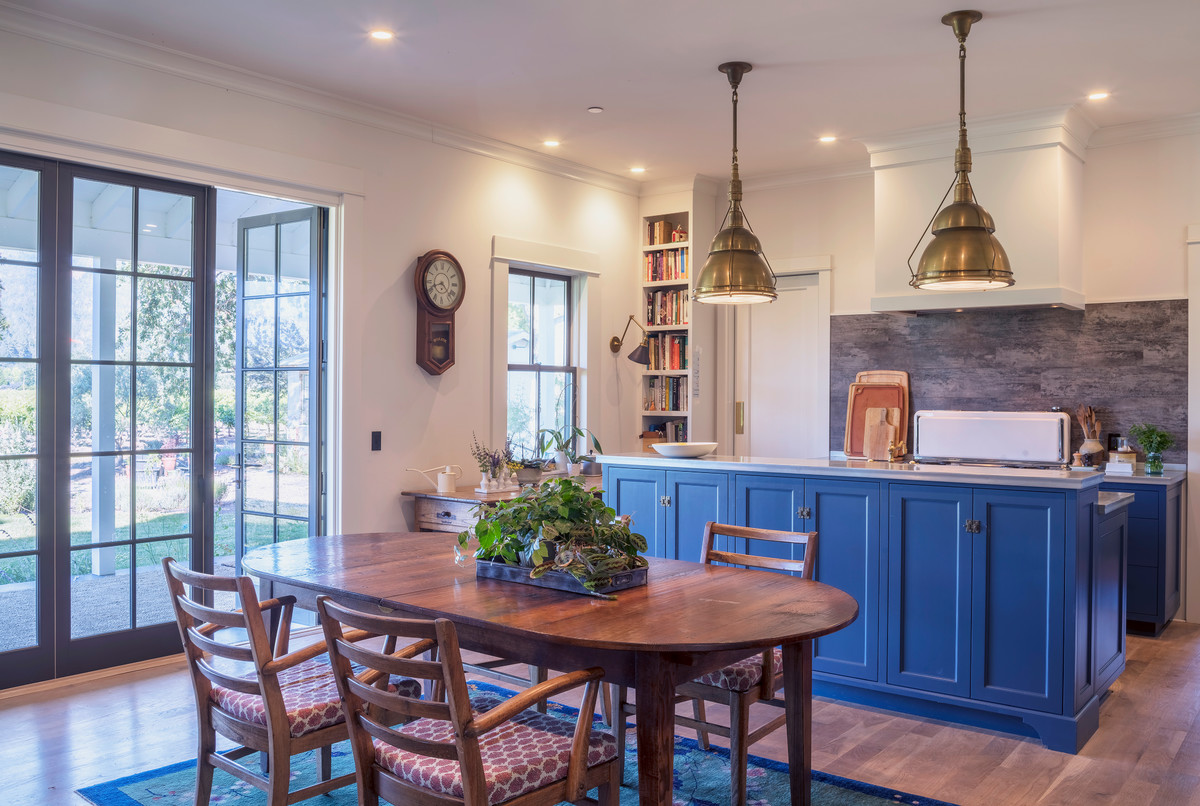 Inspiration pour une cuisine américaine rustique avec un placard à porte shaker, des portes de placard bleues, une crédence grise, un sol en bois brun et îlot.