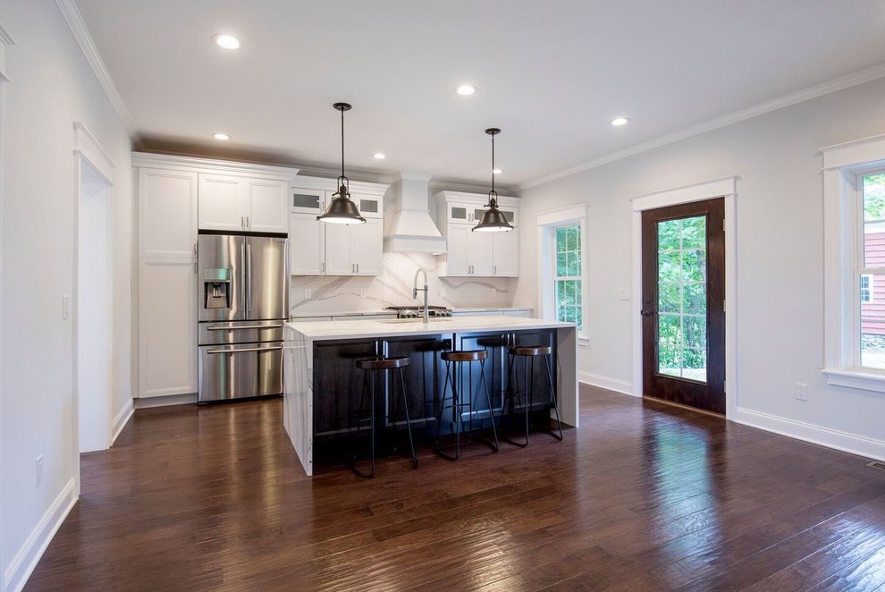 Mid-sized transitional single-wall dark wood floor and brown floor eat-in kitchen photo in New York with an undermount sink, recessed-panel cabinets, white cabinets, quartz countertops, white backsplash, stone slab backsplash, stainless steel appliances and an island