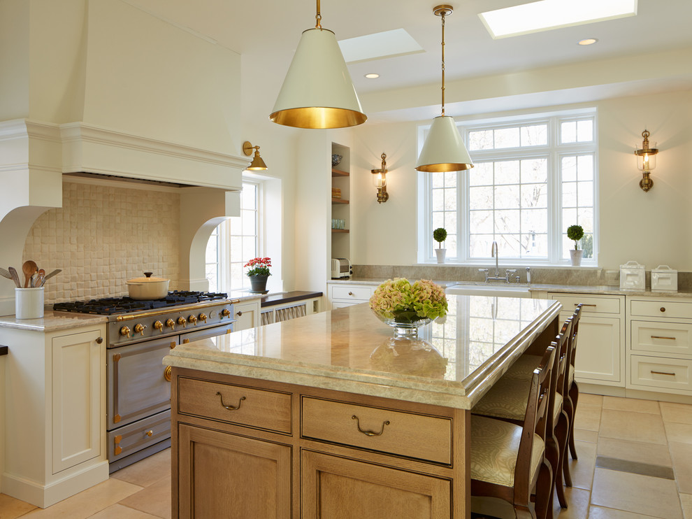 Lantlig inredning av ett kök, med en rustik diskho, skåp i shakerstil, vita skåp, beige stänkskydd, rostfria vitvaror och en köksö