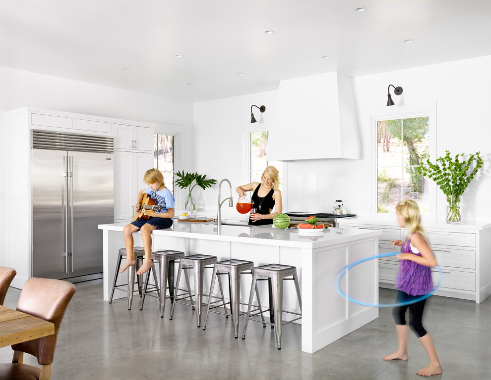 オースティンにあるトランジショナルスタイルのおしゃれなキッチン (シェーカースタイル扉のキャビネット、白いキャビネット、シルバーの調理設備、コンクリートの床) の写真