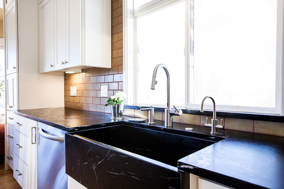 Exempel på ett avskilt, mellanstort lantligt svart svart l-kök, med en rustik diskho, skåp i shakerstil, vita skåp, bänkskiva i täljsten, grönt stänkskydd, stänkskydd i keramik, rostfria vitvaror, ljust trägolv, en köksö och gult golv