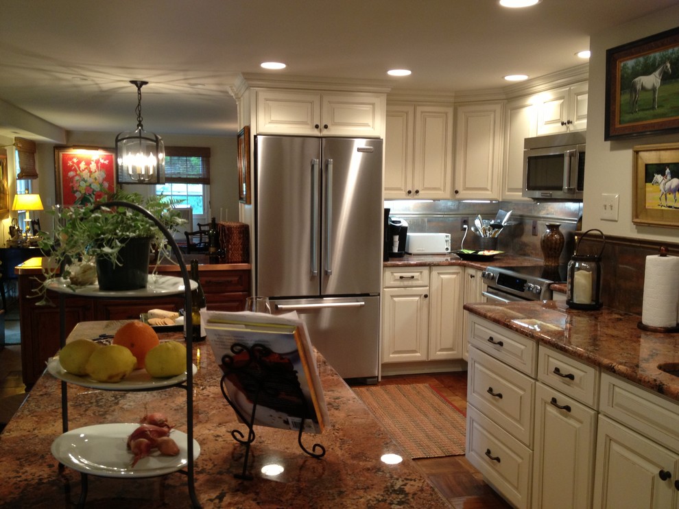 Exemple d'une cuisine américaine chic avec un placard avec porte à panneau surélevé, des portes de placard beiges, un plan de travail en granite et un électroménager en acier inoxydable.