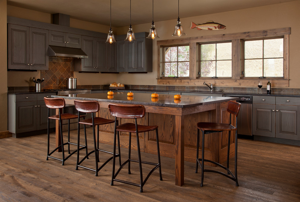 Rustik inredning av ett mellanstort l-kök, med en undermonterad diskho, luckor med upphöjd panel, bruna skåp, brunt stänkskydd, rostfria vitvaror, mörkt trägolv och en köksö