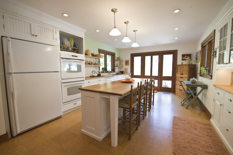 Example of a cottage eat-in kitchen design in Philadelphia with white appliances, white cabinets and white backsplash