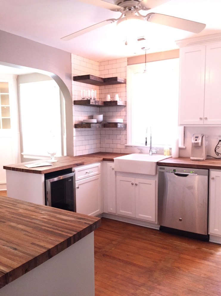 Inspiration for a mid-sized cottage u-shaped medium tone wood floor and brown floor eat-in kitchen remodel in Richmond with a farmhouse sink, shaker cabinets, white cabinets, wood countertops, white backsplash, stainless steel appliances and no island