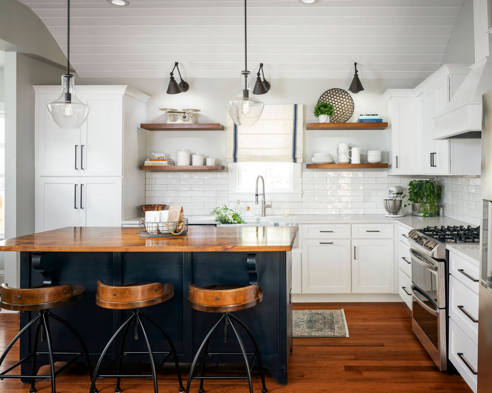 Inredning av ett lantligt mellanstort vit vitt kök, med en rustik diskho, skåp i shakerstil, vita skåp, bänkskiva i kvarts, vitt stänkskydd, stänkskydd i keramik, rostfria vitvaror, mellanmörkt trägolv, en köksö och brunt golv
