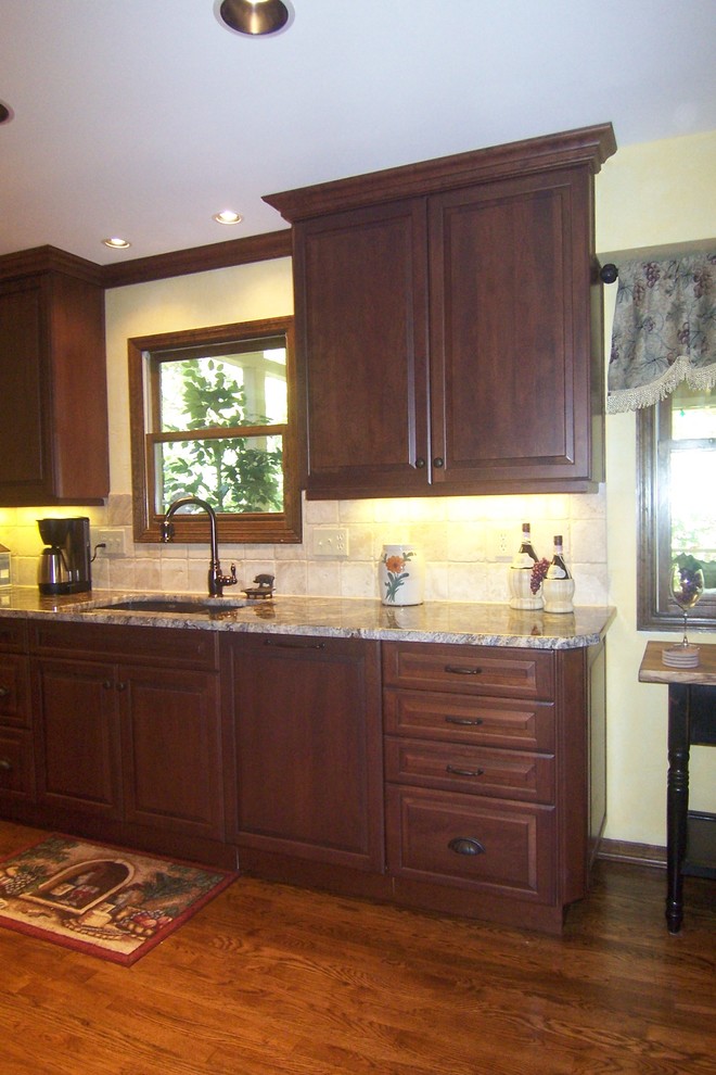 Example of a large country u-shaped medium tone wood floor eat-in kitchen design in Cincinnati with an undermount sink, raised-panel cabinets, granite countertops, white backsplash, stone tile backsplash, paneled appliances, no island and white cabinets