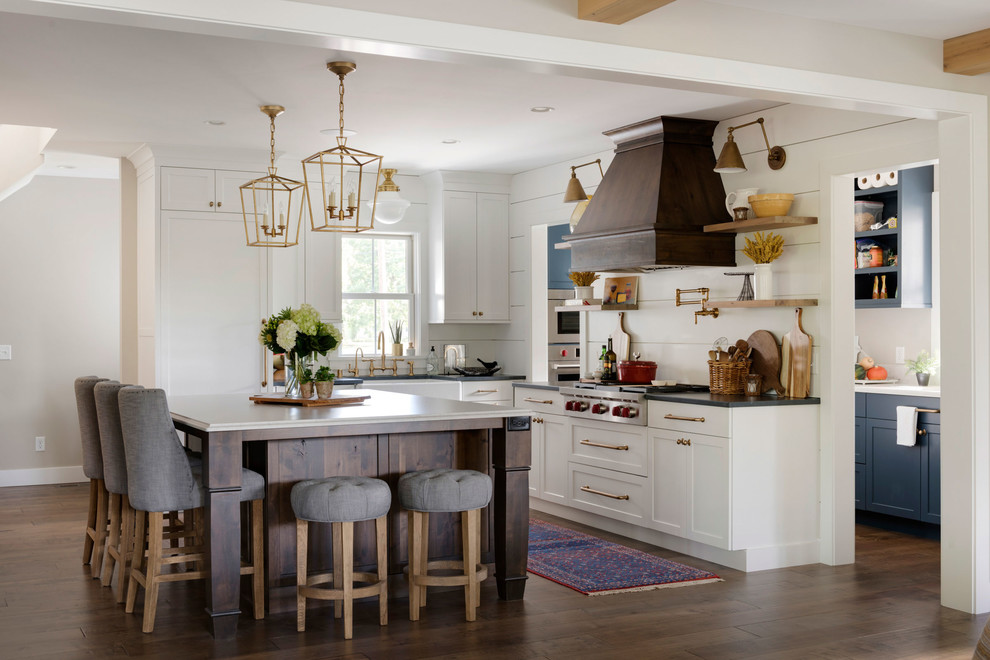 Example of a large farmhouse l-shaped dark wood floor and brown floor eat-in kitchen design in Minneapolis with a farmhouse sink, stainless steel appliances, an island, shaker cabinets, white cabinets, gray countertops, quartz countertops and white backsplash