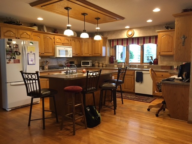 Inredning av ett lantligt stort kök, med en undermonterad diskho, släta luckor, vita skåp, bänkskiva i kvarts, grått stänkskydd, stänkskydd i keramik, integrerade vitvaror, mellanmörkt trägolv, en köksö och brunt golv