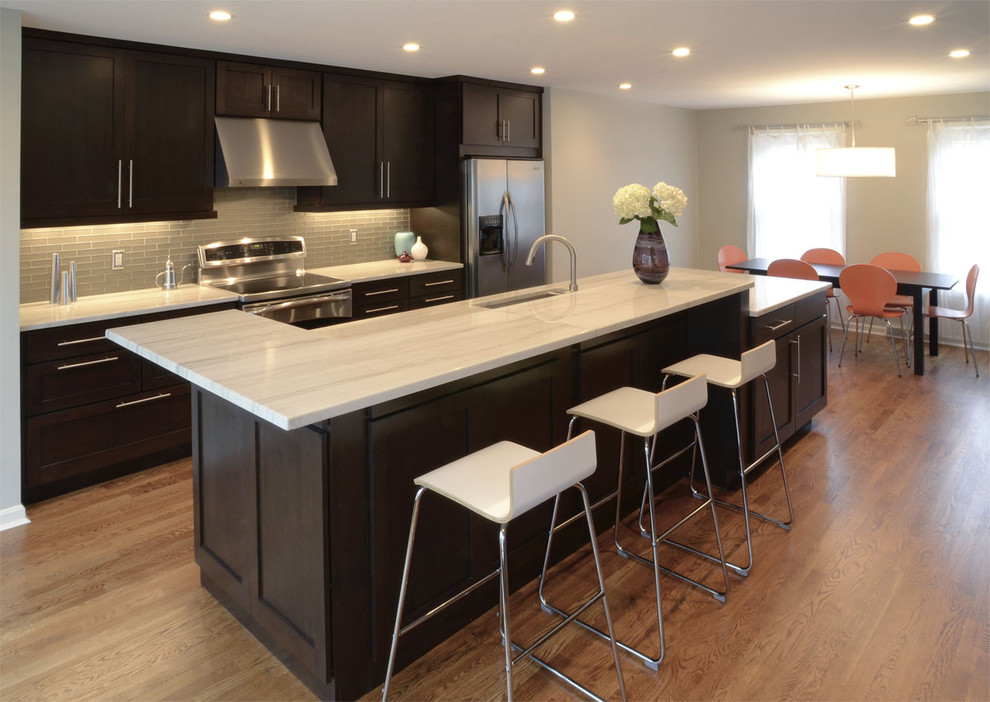 Inspiration for a transitional galley eat-in kitchen remodel in Cincinnati with stainless steel appliances, an undermount sink, shaker cabinets, dark wood cabinets and glass tile backsplash