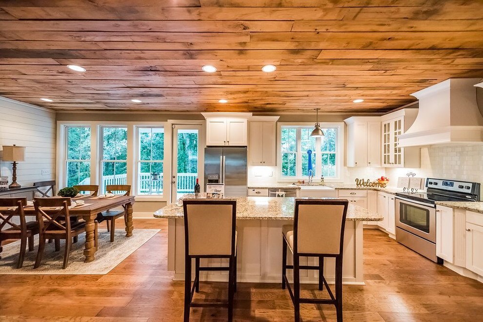 Exempel på ett mellanstort lantligt flerfärgad flerfärgat kök, med en rustik diskho, luckor med infälld panel, vita skåp, granitbänkskiva, vitt stänkskydd, stänkskydd i tunnelbanekakel, rostfria vitvaror, mellanmörkt trägolv, en köksö och brunt golv