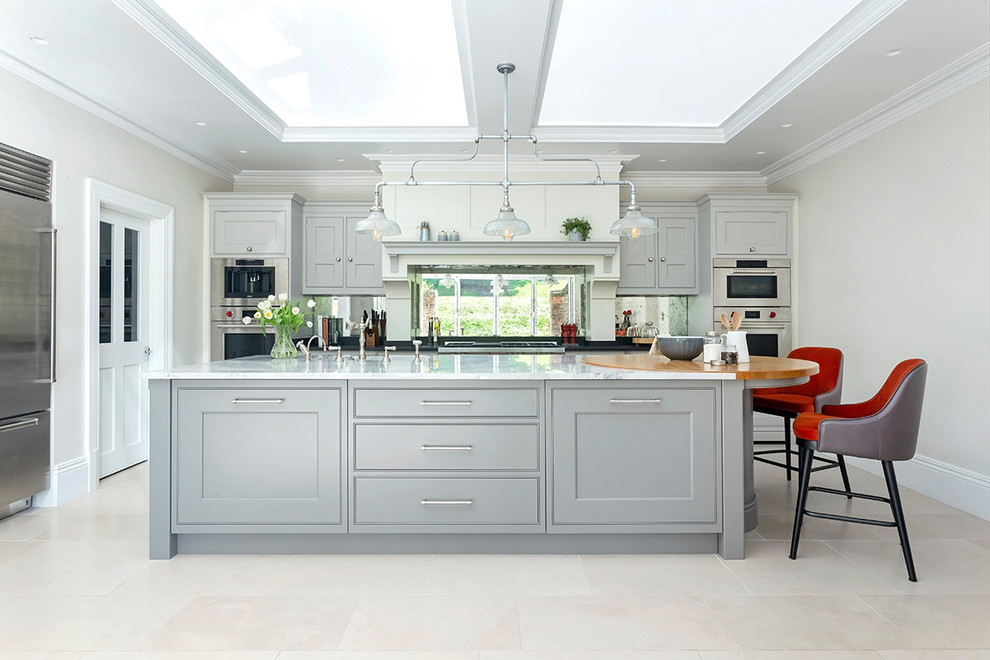 Idéer för ett stort klassiskt vit kök, med grå skåp, marmorbänkskiva, kalkstensgolv, en köksö, beiget golv, skåp i shakerstil, spegel som stänkskydd och rostfria vitvaror