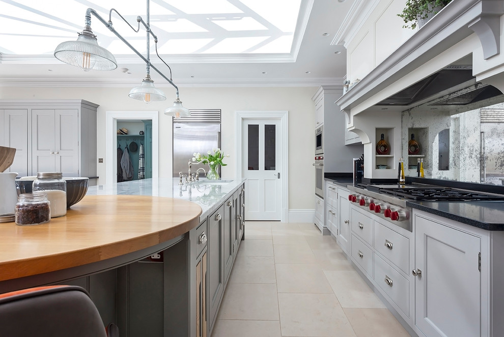 Große Klassische Wohnküche mit flächenbündigen Schrankfronten, grauen Schränken, Marmor-Arbeitsplatte, Kalkstein, Kücheninsel und beigem Boden in Surrey