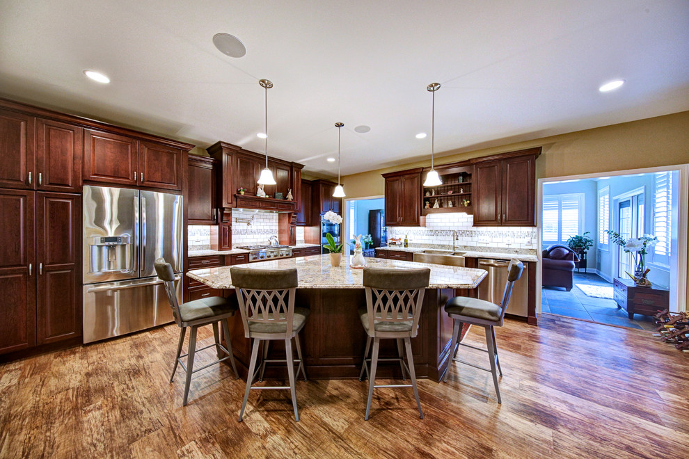Exempel på ett stort, avskilt klassiskt l-kök, med en rustik diskho, luckor med upphöjd panel, skåp i mörkt trä, granitbänkskiva, vitt stänkskydd, stänkskydd i keramik, rostfria vitvaror, vinylgolv, en köksö och brunt golv