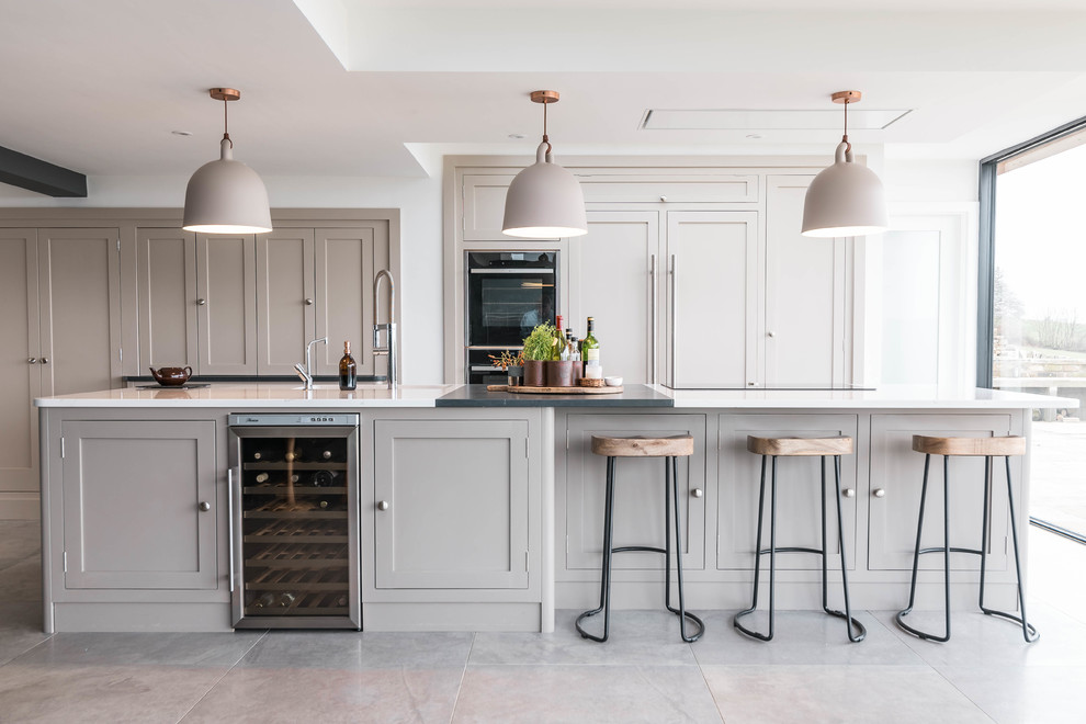 Esempio di una cucina country di medie dimensioni con ante in stile shaker, ante beige, elettrodomestici neri, pavimento grigio e top bianco