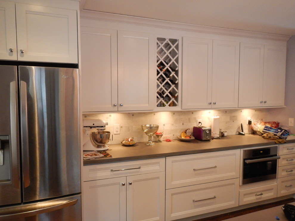 Cette photo montre une grande cuisine tendance avec un placard à porte shaker, des portes de placard blanches, un plan de travail en béton et un électroménager en acier inoxydable.