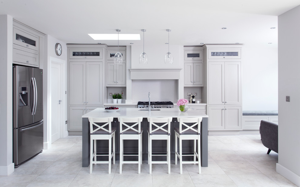 Exempel på ett klassiskt kök, med en undermonterad diskho, luckor med infälld panel, grå skåp, rostfria vitvaror och en köksö